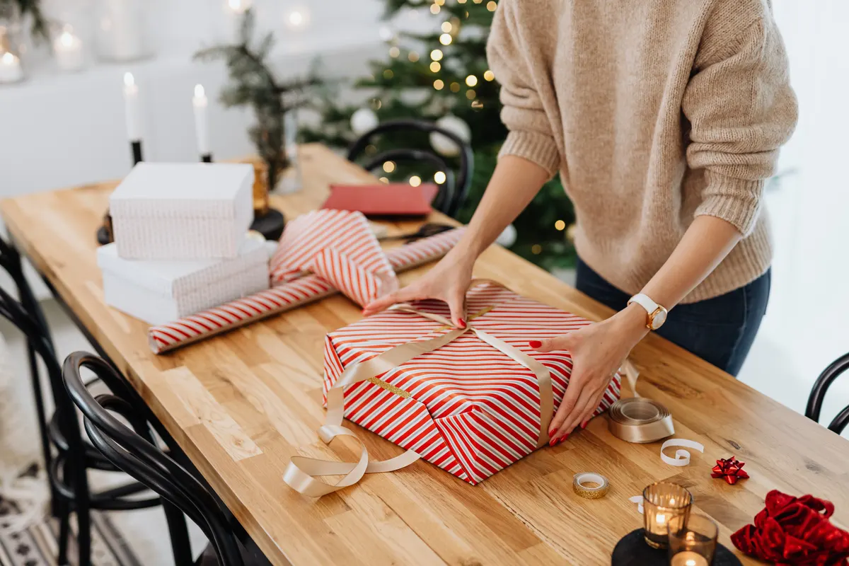 Person verpackt entspannt Geschenke am Tisch zu Hause