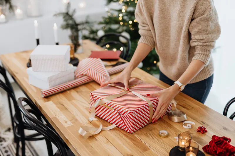 Person verpackt ein reserviertes Geschenk aus einer Wunschliste Person verpackt ein reserviertes Geschenk aus einer Wunschliste