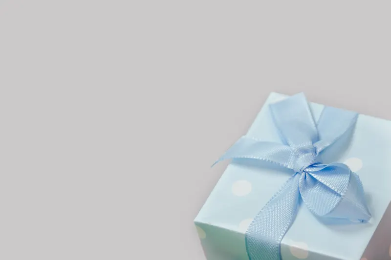 Person verpackt ein Geschenk zur Babyerstausstattung mit Geschenkpapier Person verpackt ein Geschenk zur Babyerstausstattung mit Geschenkpapier