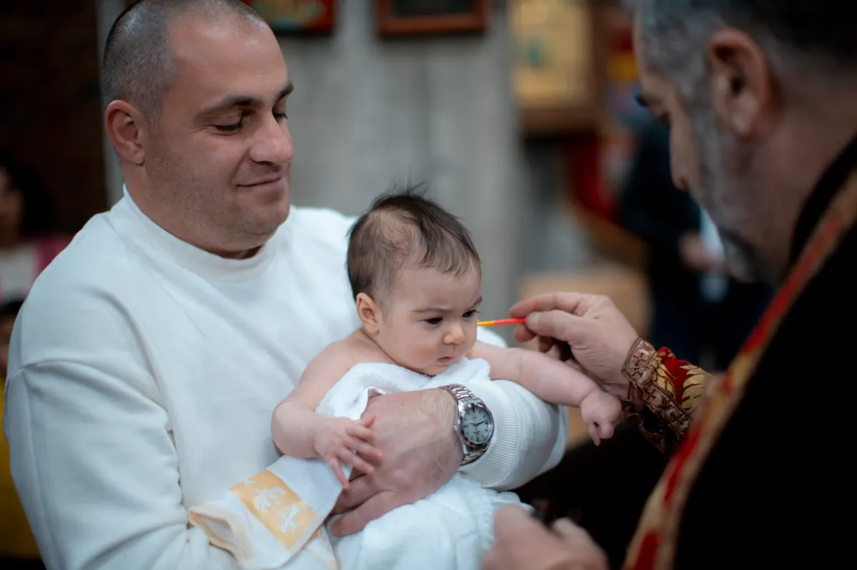 Taufpaten halten ein Baby bei einer Familienfeier Taufpaten halten ein Baby bei einer Familienfeier