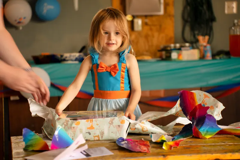 Person verpackt ein buntes Geschenk für ein Kind Person verpackt ein buntes Geschenk für ein Kind