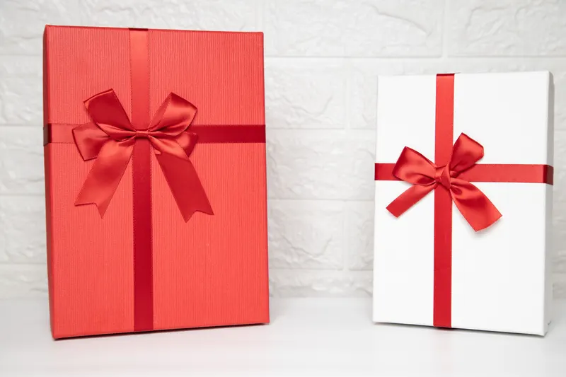 Person verpackt ein Geschenk zur Kommunion mit Geschenkpapier Person verpackt ein Geschenk zur Kommunion mit Geschenkpapier