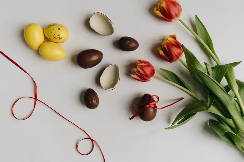 Person verpackt ein Ostergeschenk mit buntem Geschenkpapier Person verpackt ein Ostergeschenk mit buntem Geschenkpapier