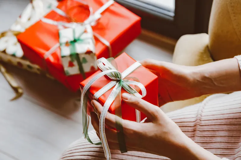 Person verpackt ein Weihnachtsgeschenk mit Geschenkpapier Person verpackt ein Weihnachtsgeschenk mit Geschenkpapier