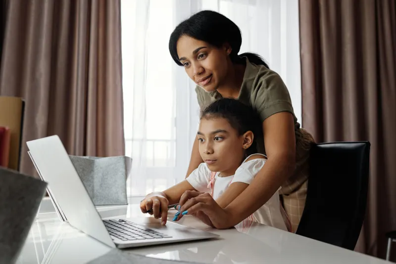 Eltern und Kind stellen gemeinsam eine Einschulungs-Wunschliste am Laptop zusammen Eltern und Kind stellen gemeinsam eine Einschulungs-Wunschliste am Laptop zusammen