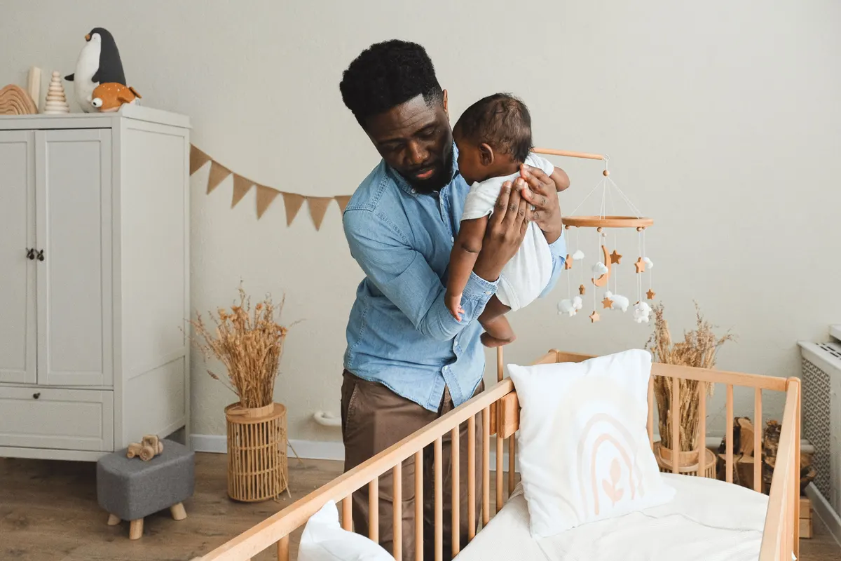 Familie betrachtet Baby-Erstausstattung in einem Kinderzimmer Familie betrachtet Baby-Erstausstattung in einem Kinderzimmer